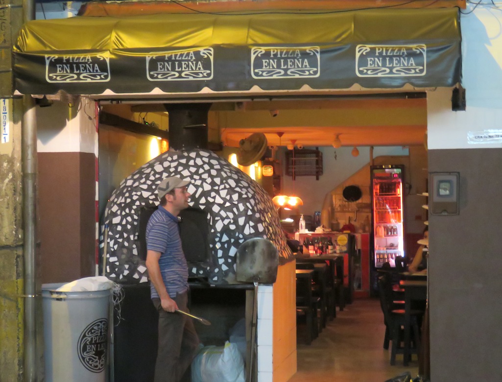 Pizza en Leña, con el horno de ladrillo al frente y el dueño cocinando