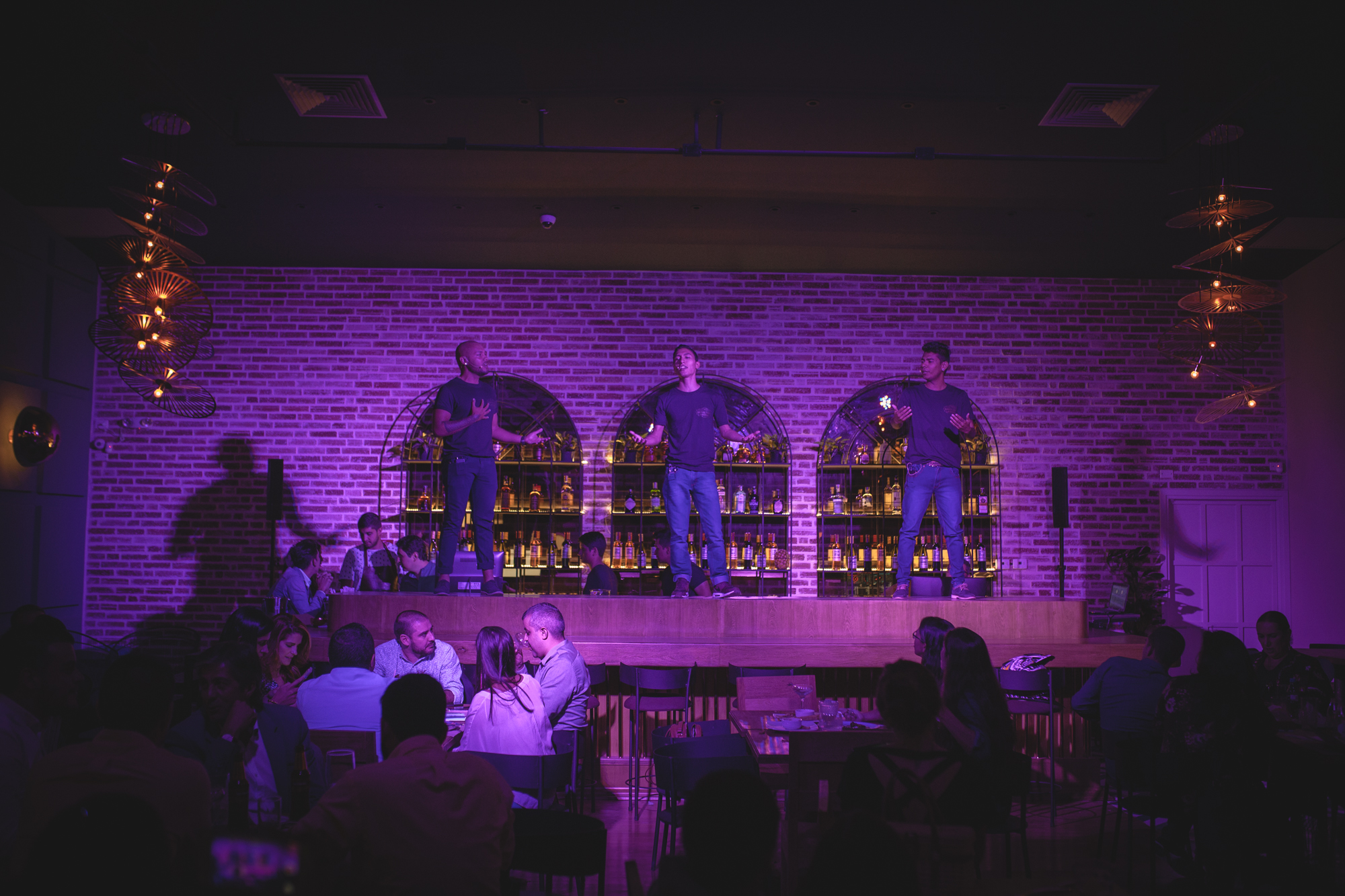 A trio of chicos performing from atop the bar