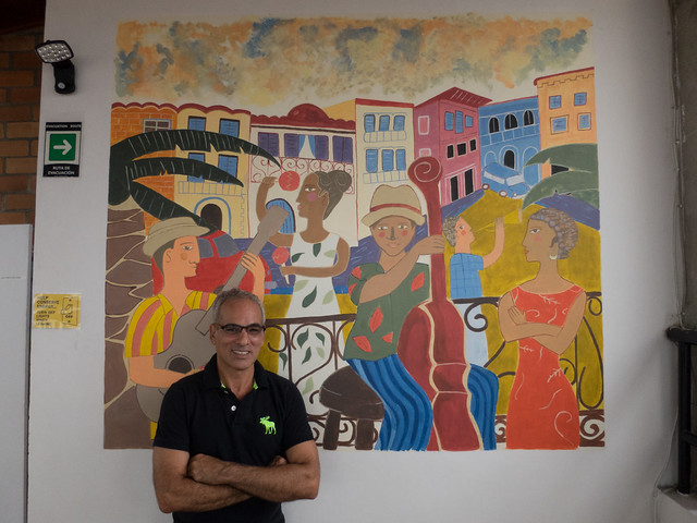 Joel Joel, the owner, in front of a painting by one of his guests