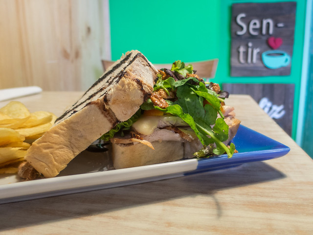 Sándwich de pavo con tomates cherry, queso emmental, lechuga, maní confitado y vinagre balsámico en pan artesanal