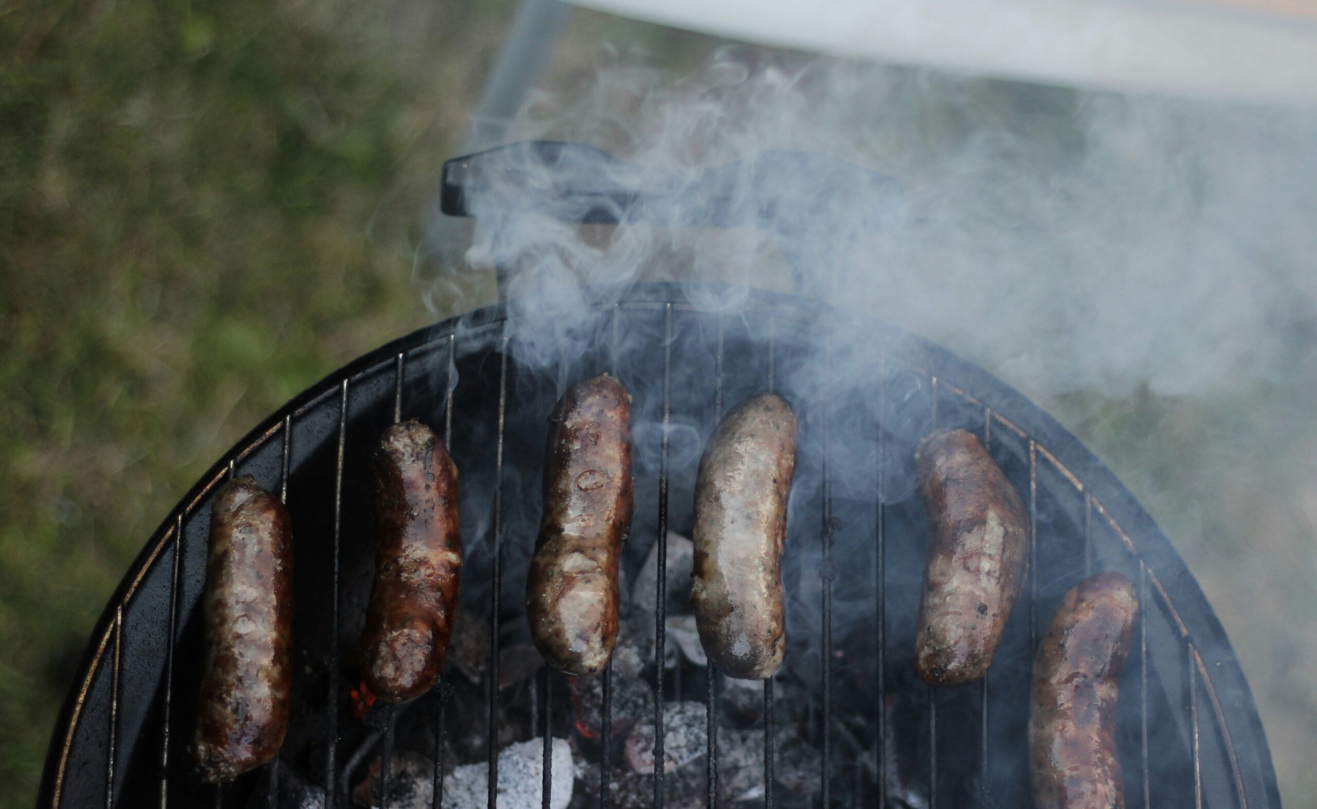 six sausages on black charcoal grill