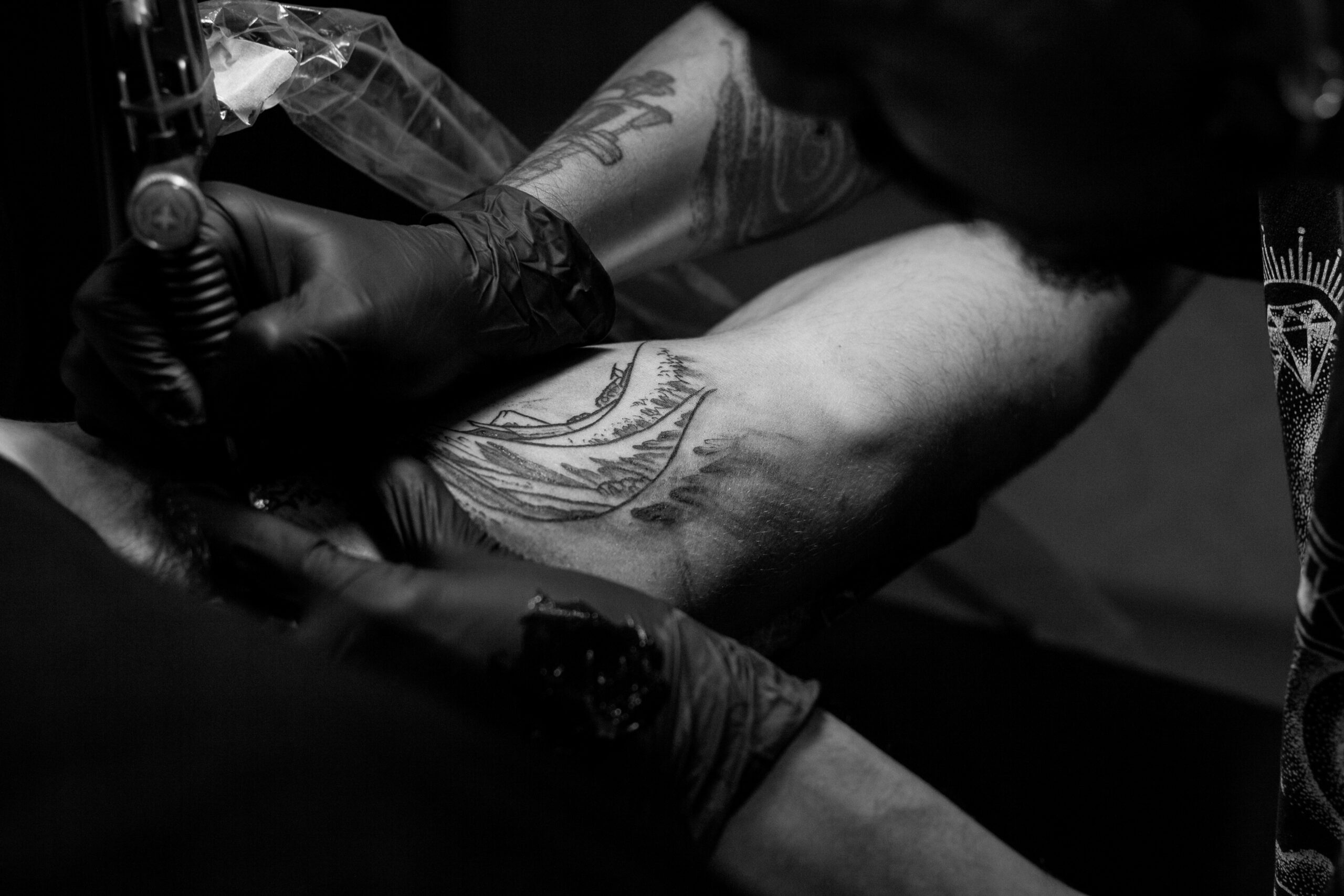 foto en escala de grises de un hombre haciendo un tatuaje