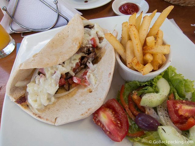 Pork giro Giro with pork, in pita bread, topped with tomato, onion, and tzatziki (cucumber-garlic sauce), service with fries and salad